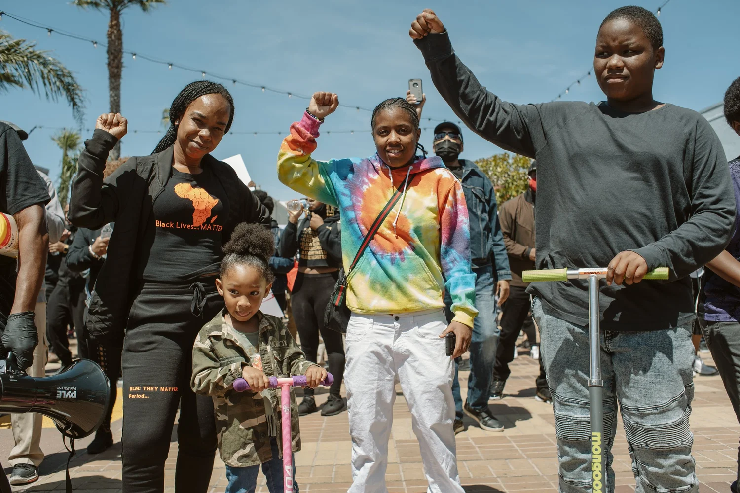 Adults and children posing with raised fists and scooters.