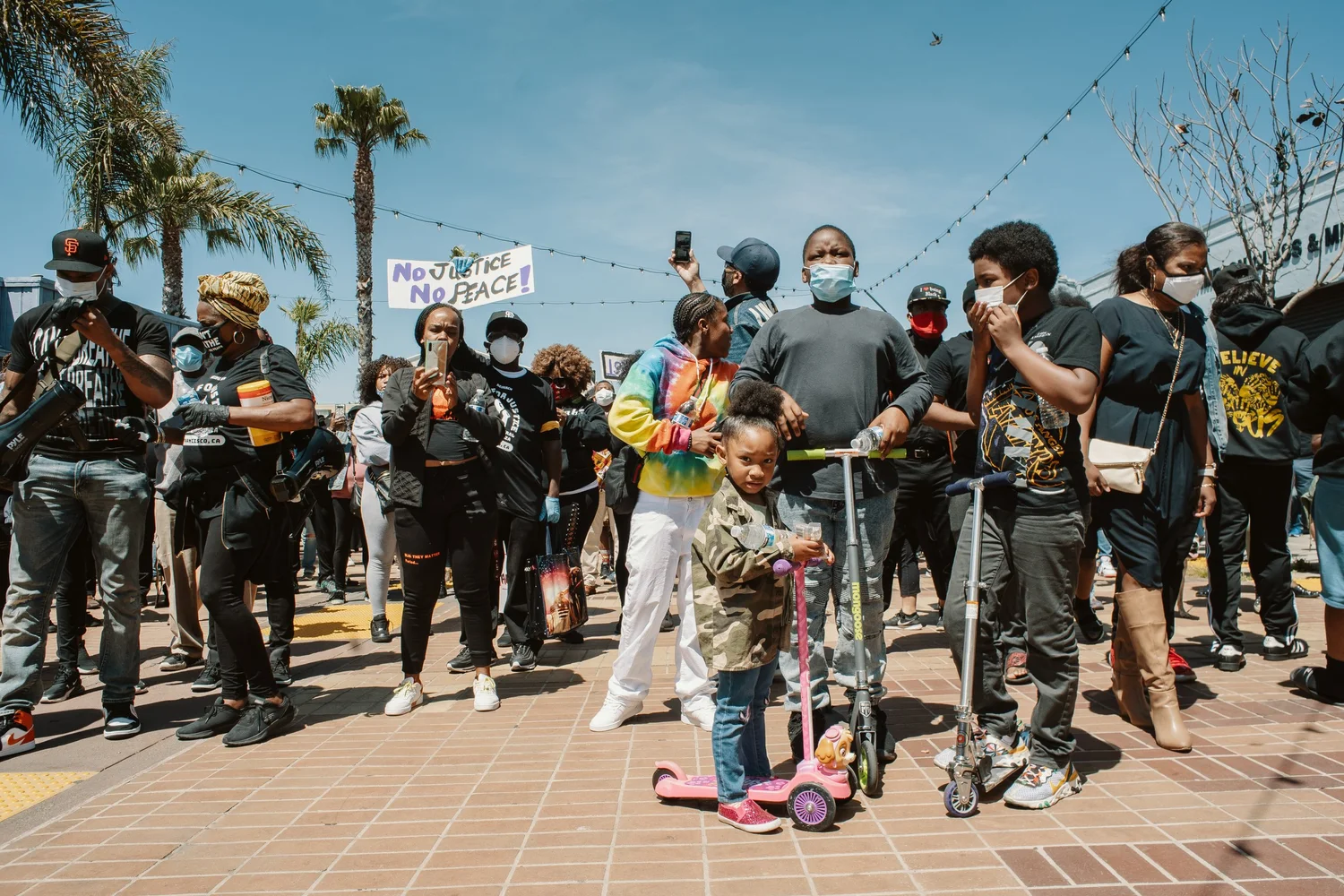 Children with scooters standing beside adults at the rally.