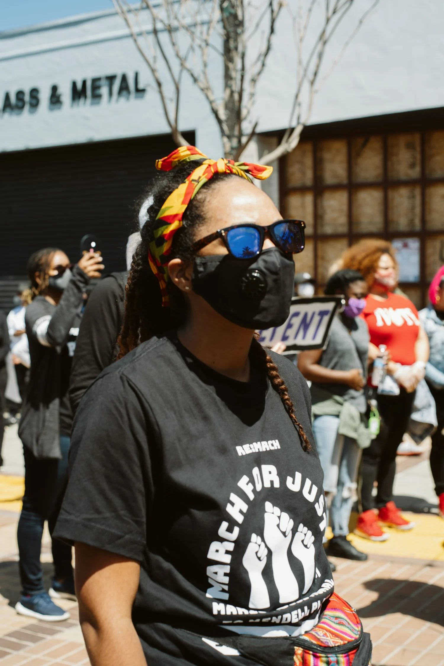 Masked participant wearing sunglasses and a colorful head wrap.