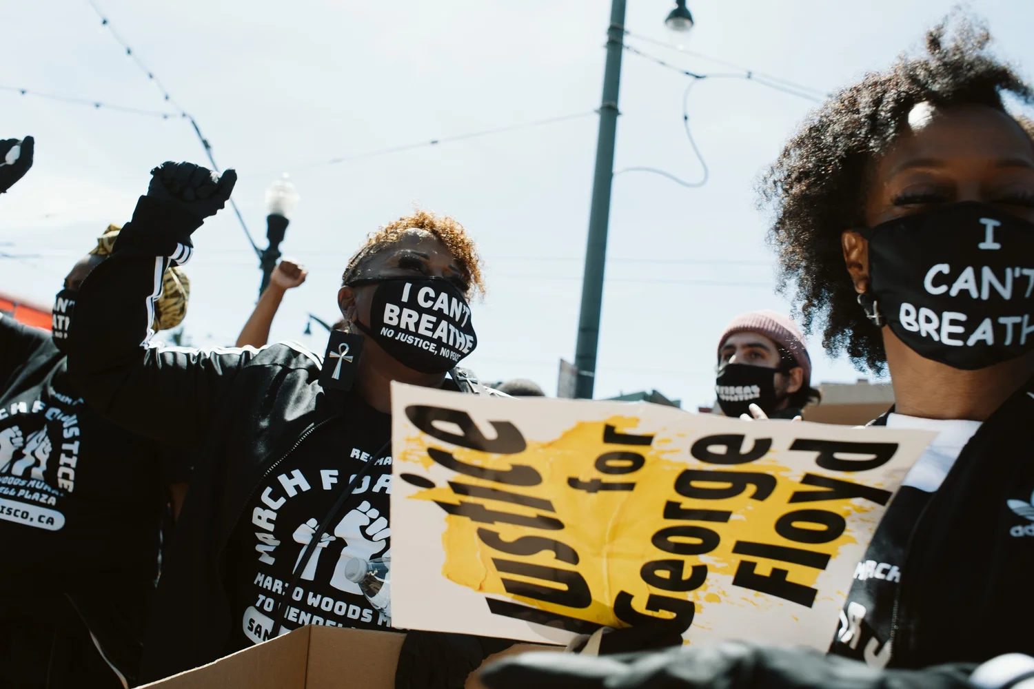 Participants raising fists beside a Justice for George Floyd sign.