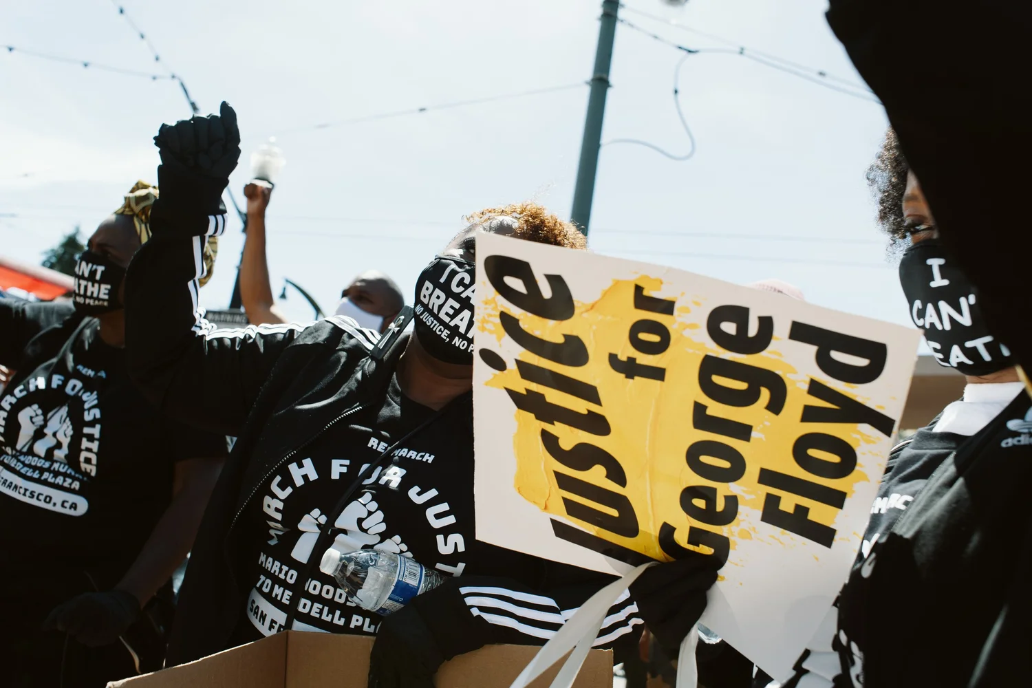 Close view of a Justice for George Floyd sign and raised fists.