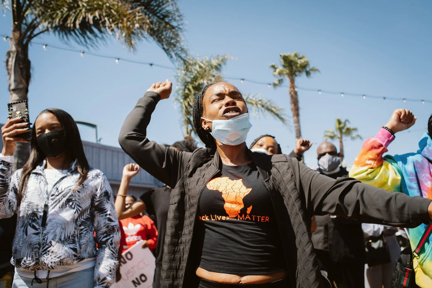 Participants raising fists beneath palm trees.