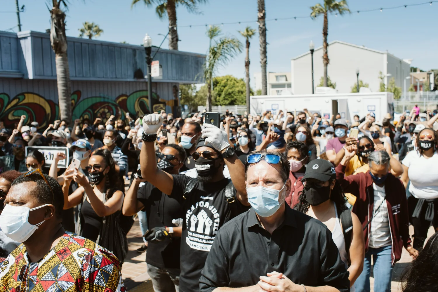 Masked crowd listening in the plaza.