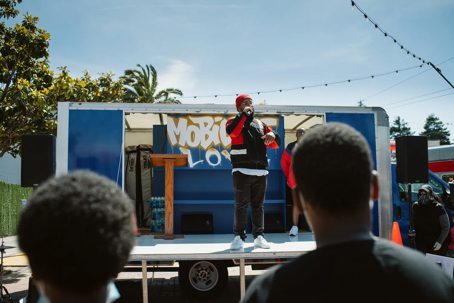 Performer holding a microphone in front of the Mobilize Love truck.