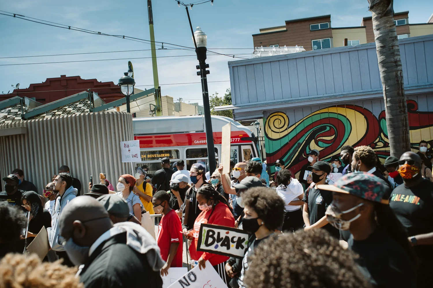 Crowd gathered near a colorful mural.