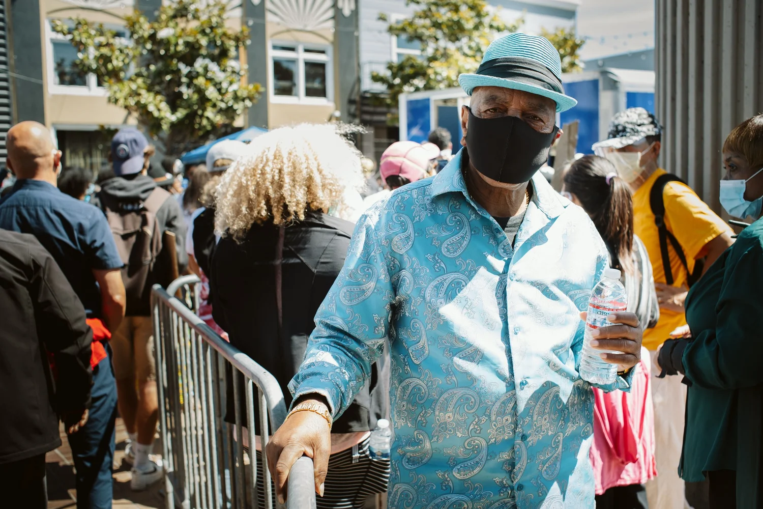 Masked attendee wearing a light blue shirt and hat.