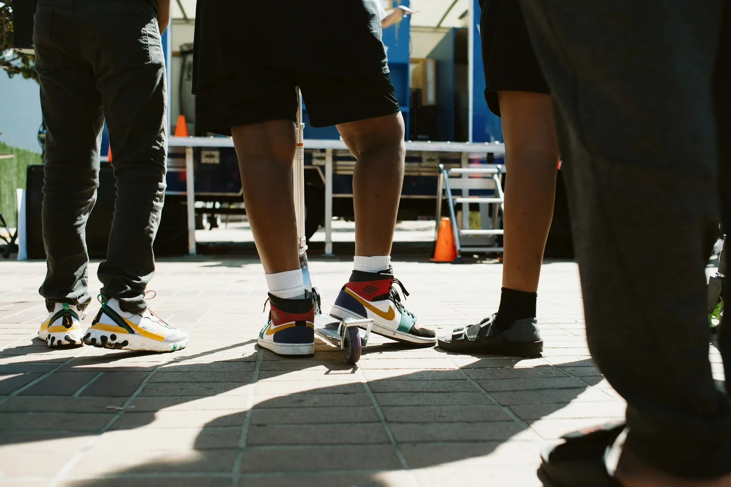 Low-angle detail of participants' shoes and shadows on the plaza.