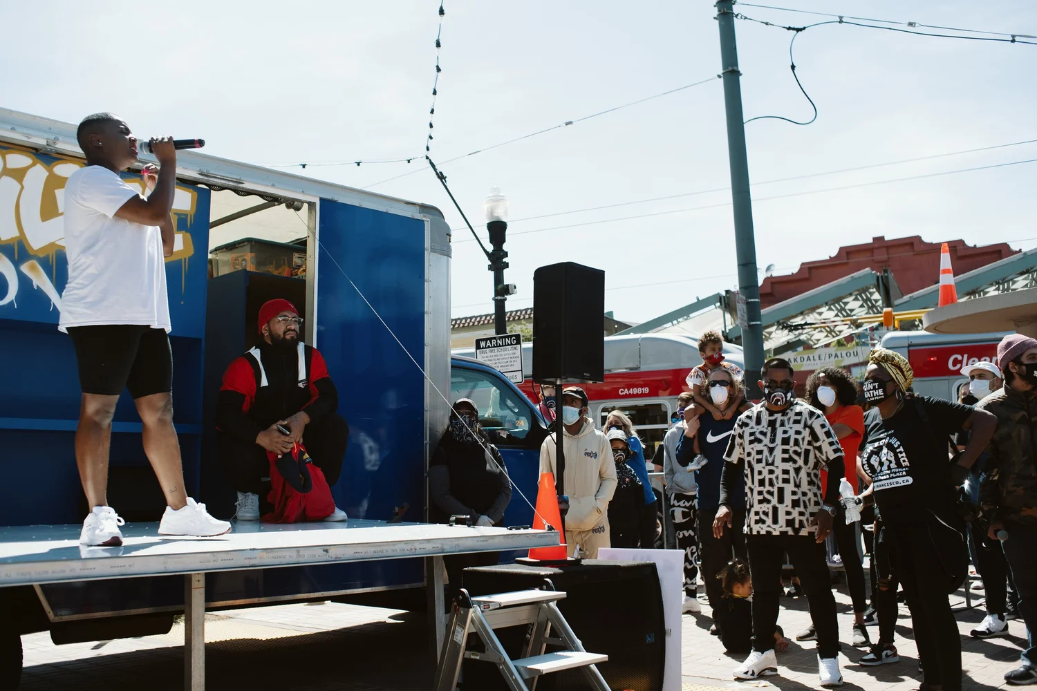 Performer in a white shirt speaking from the truck stage.