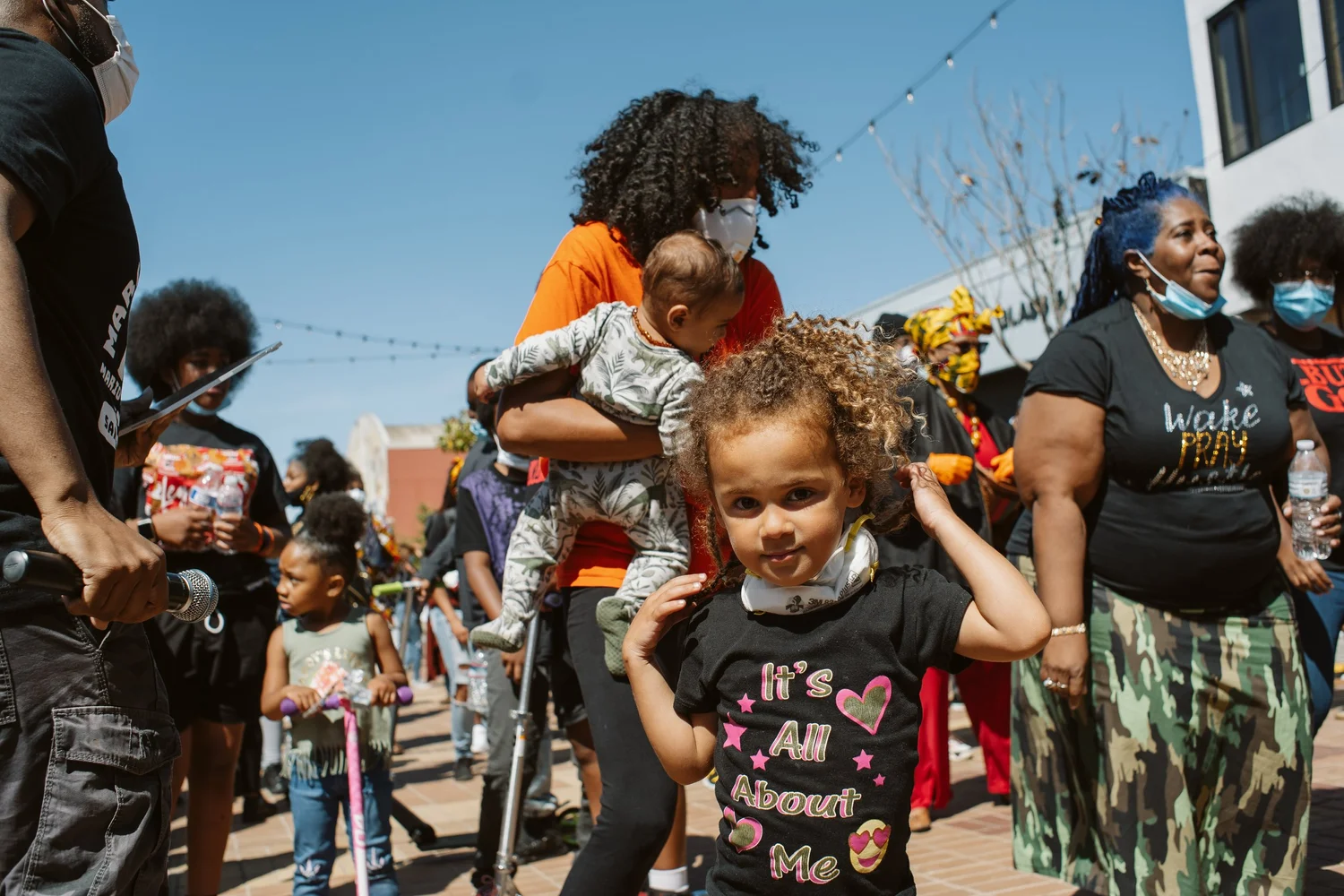 Child standing in front of adults in the crowd.