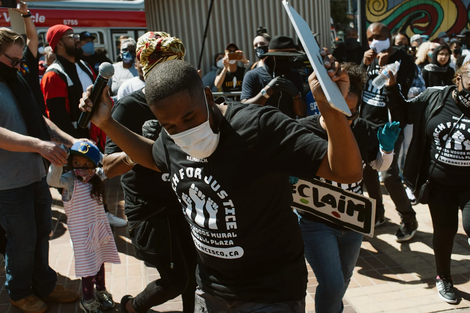 Masked participant raising both arms.