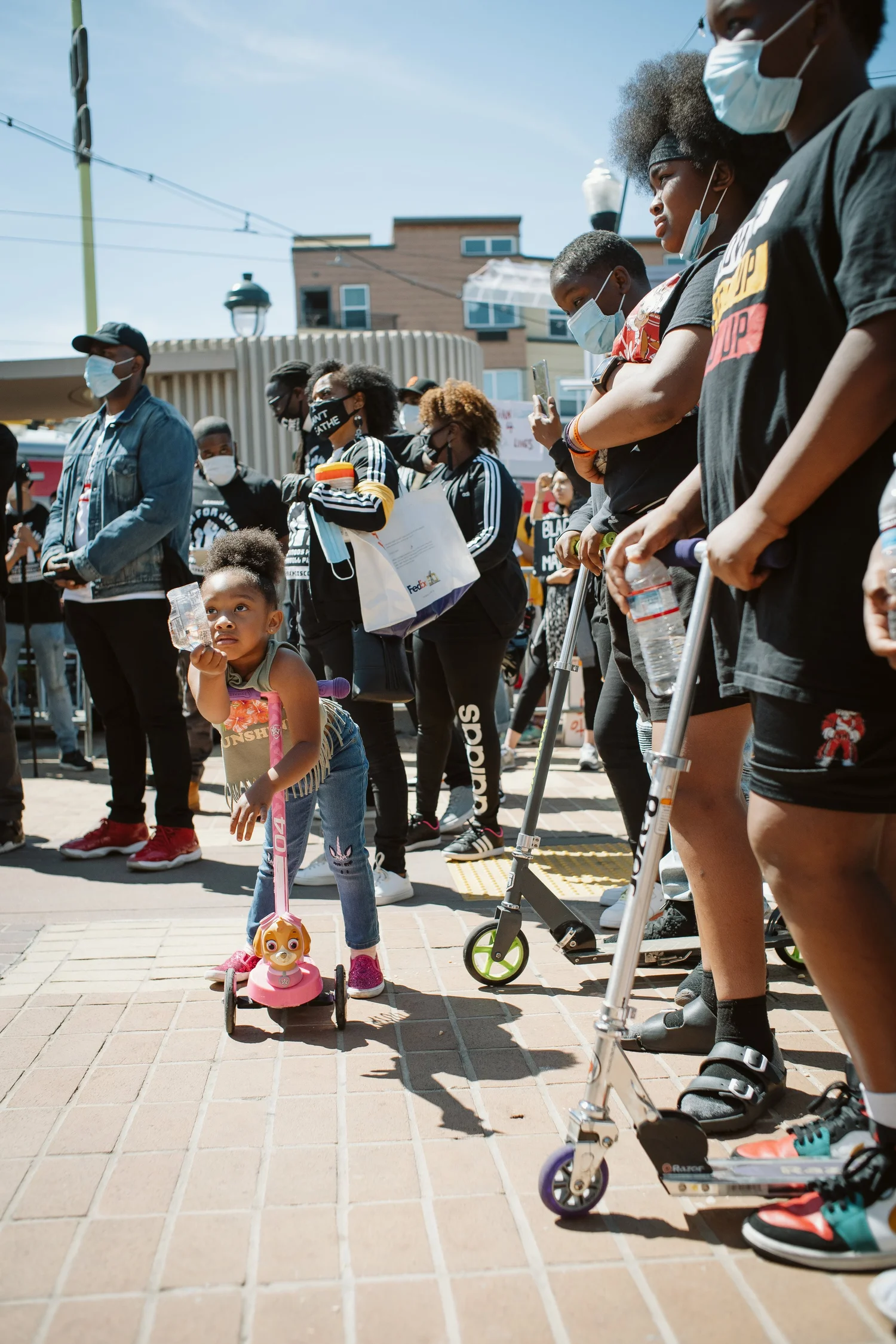 Adults and children watching beside scooters.