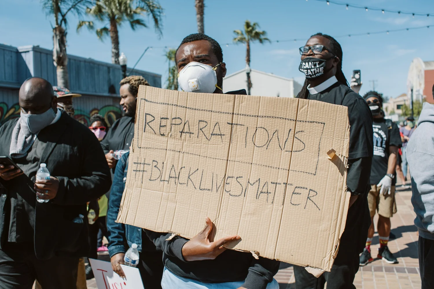 Participant holding a Reparations, Black Lives Matter sign.