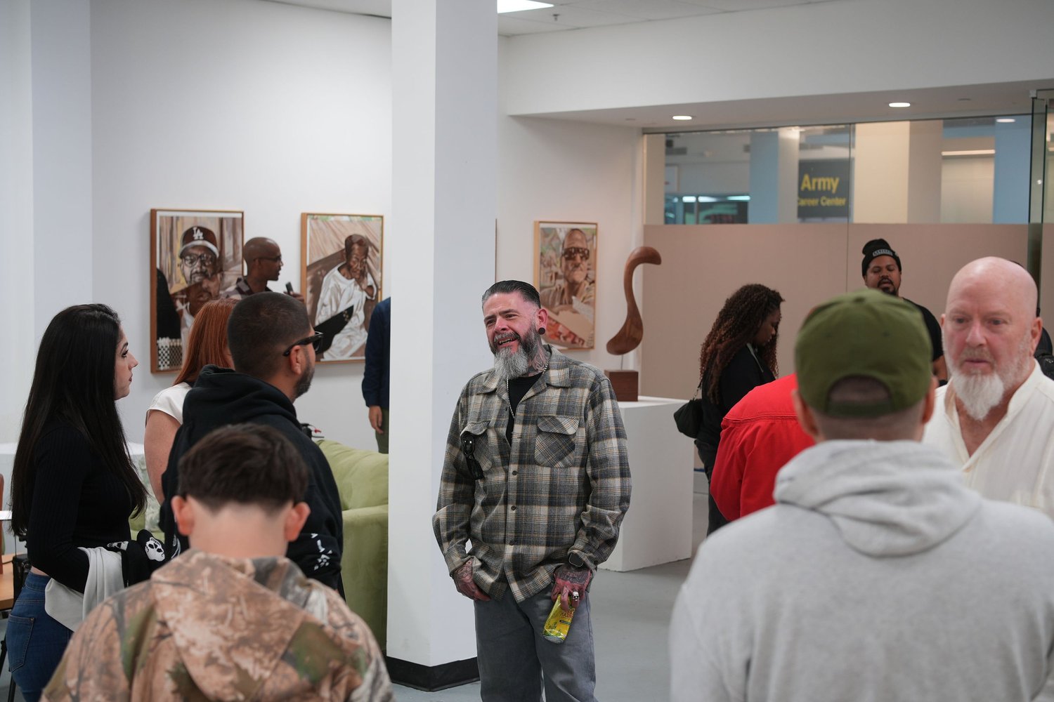 Visitors talk together among the displayed portraits.
