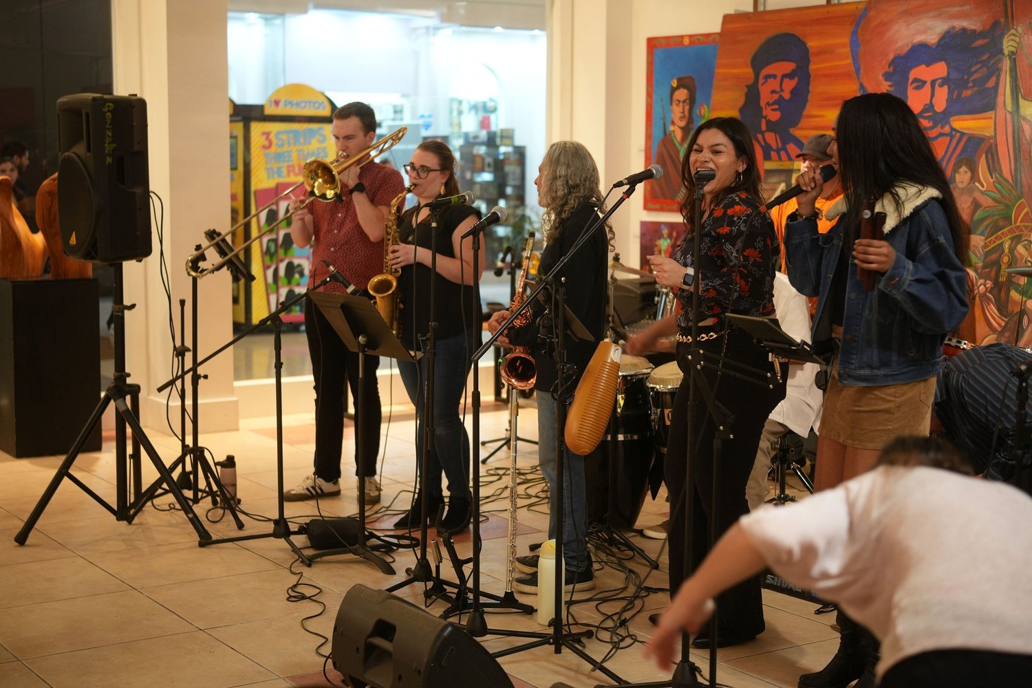 Musicians perform together in front of a colorful mural.