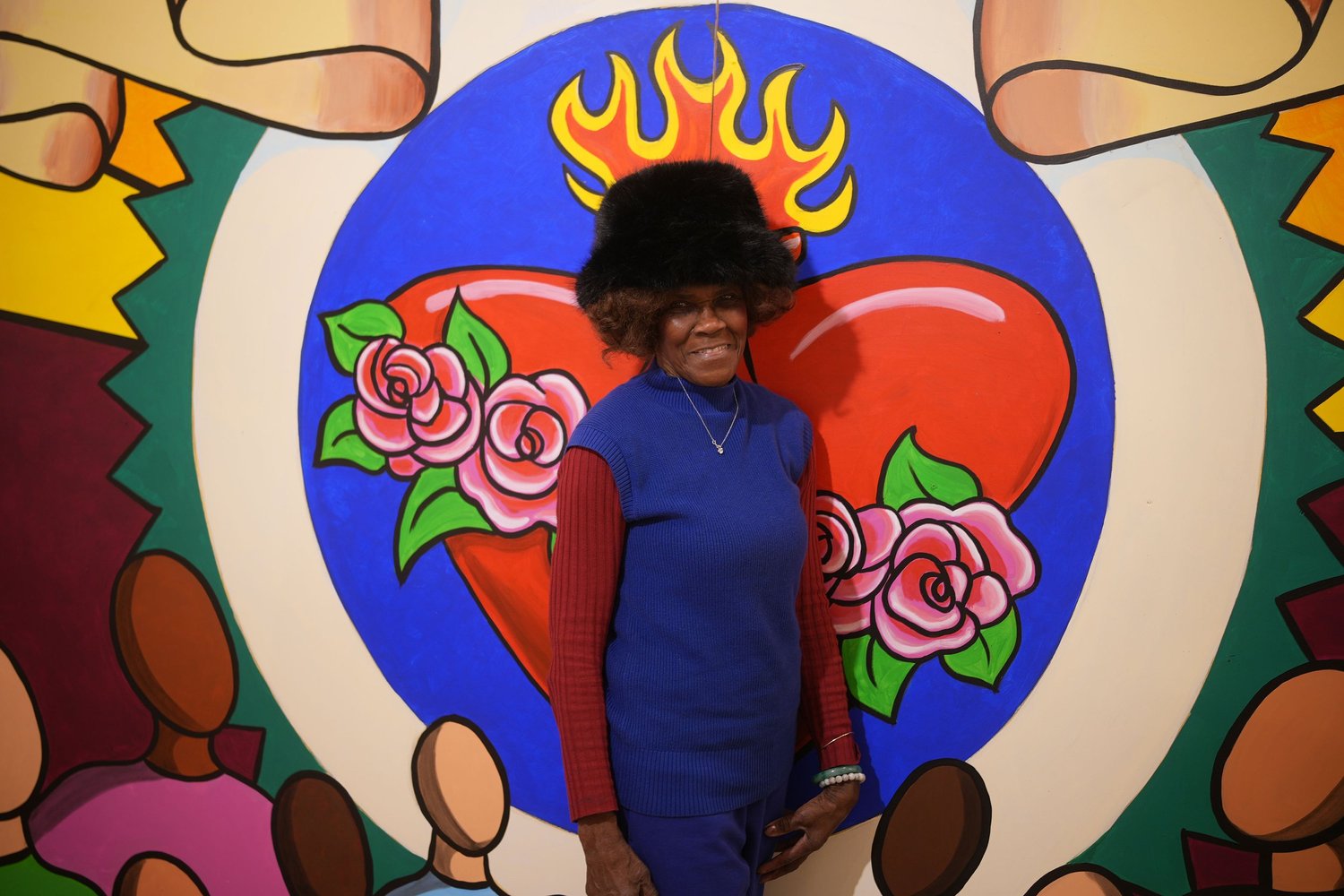 A visitor stands in front of a colorful heart mural.