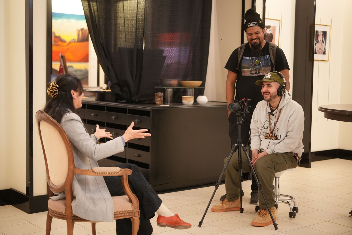 A seated interviewer speaks with two participants.
