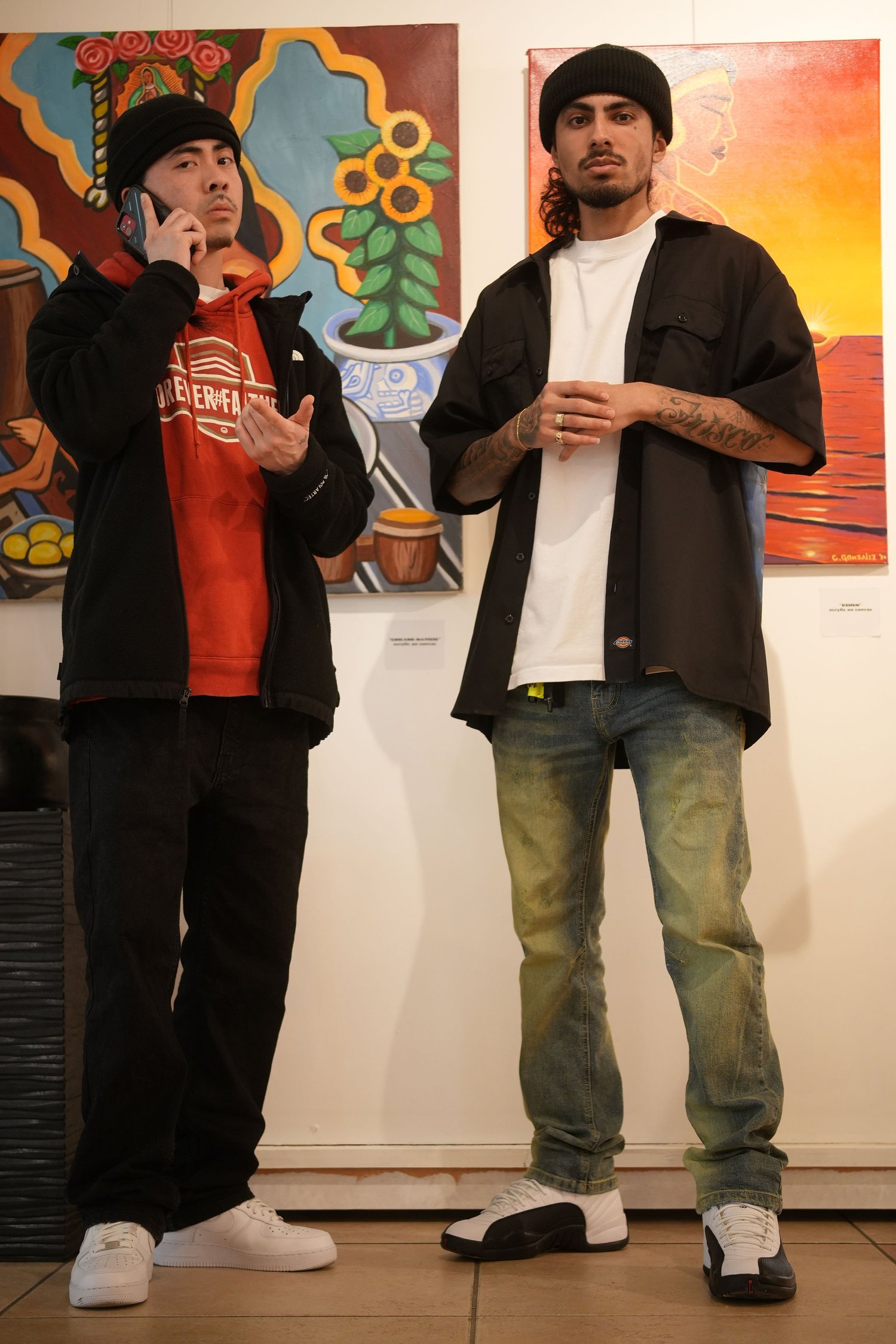 Two guests stand together in front of a mural.