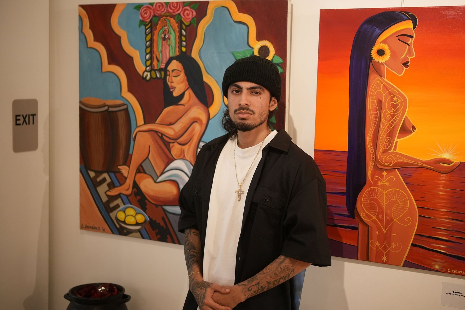 A visitor stands in front of colorful paintings.