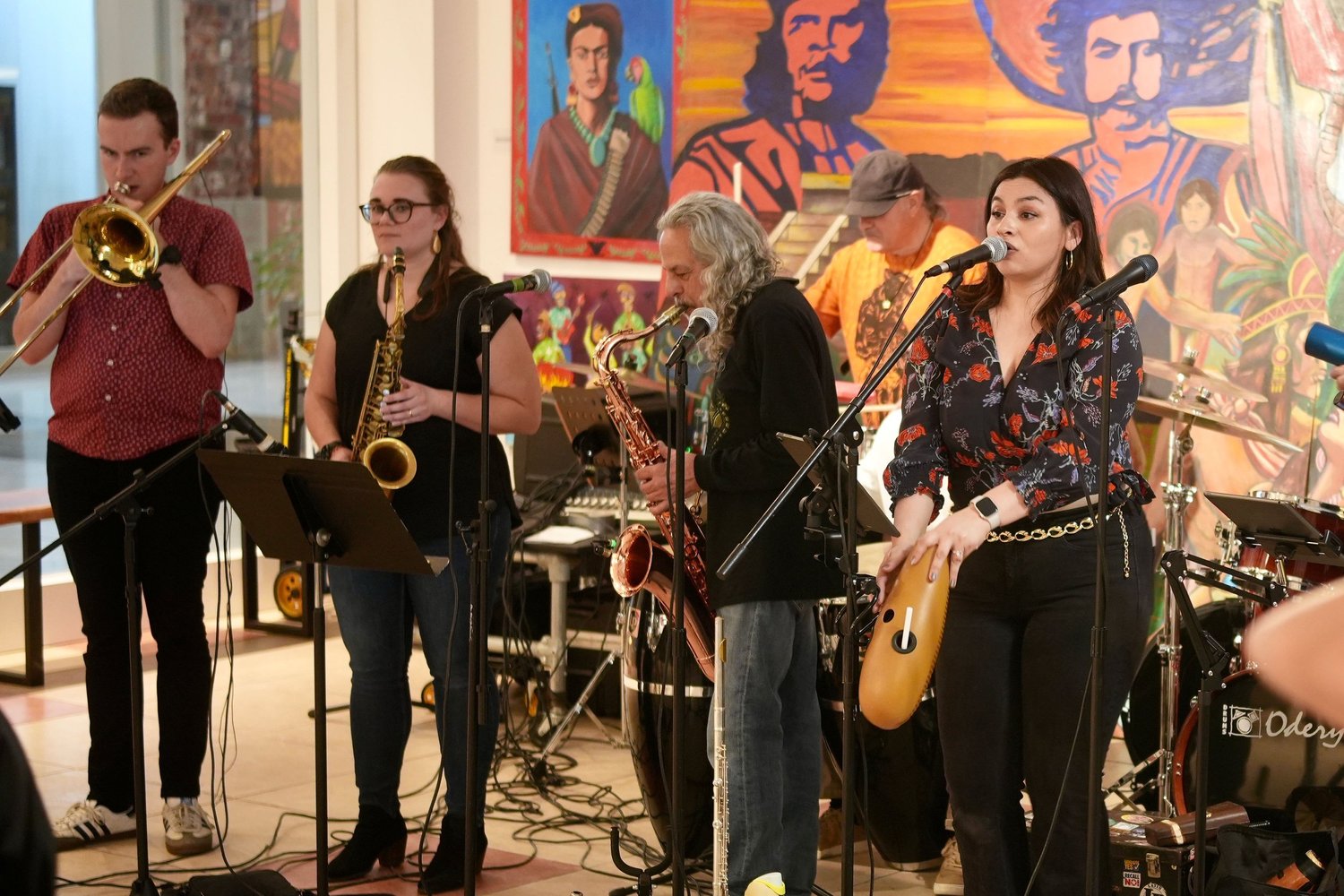 A trombonist, saxophonists, and guitarist perform together.