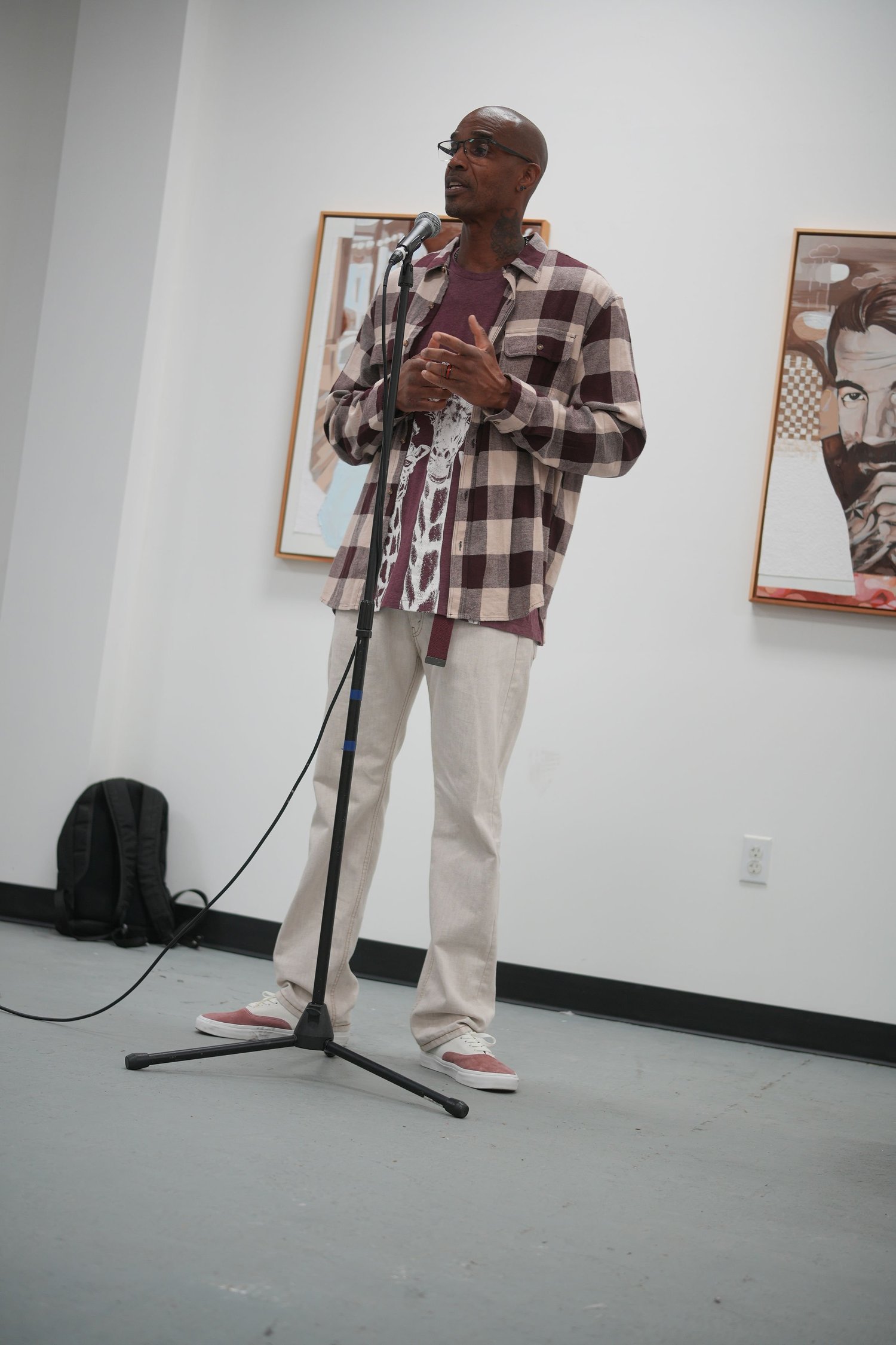 A participant speaks into a microphone beside portraits.