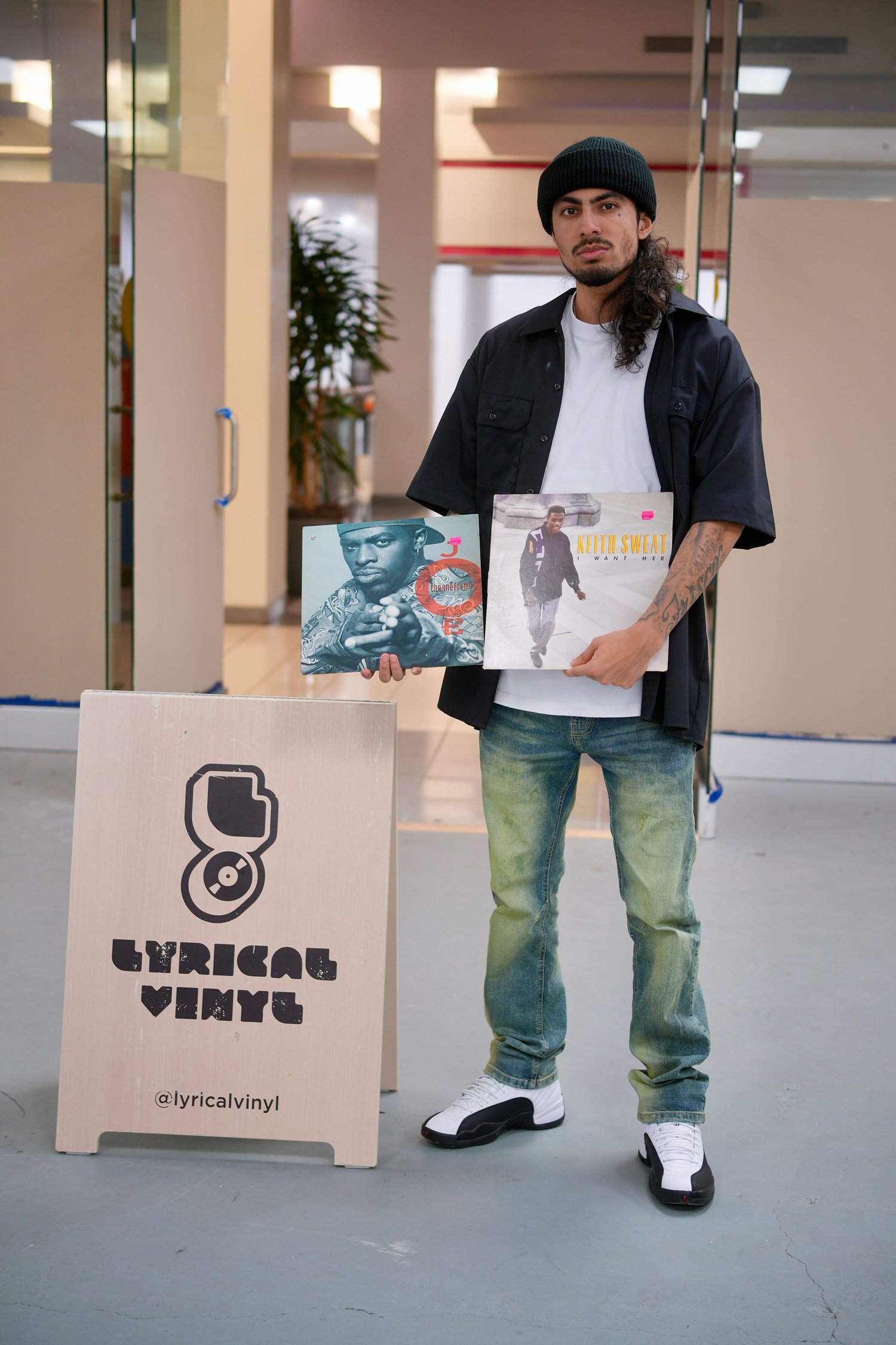 A visitor holds record sleeves beside the Lyrical Vinyl sign.