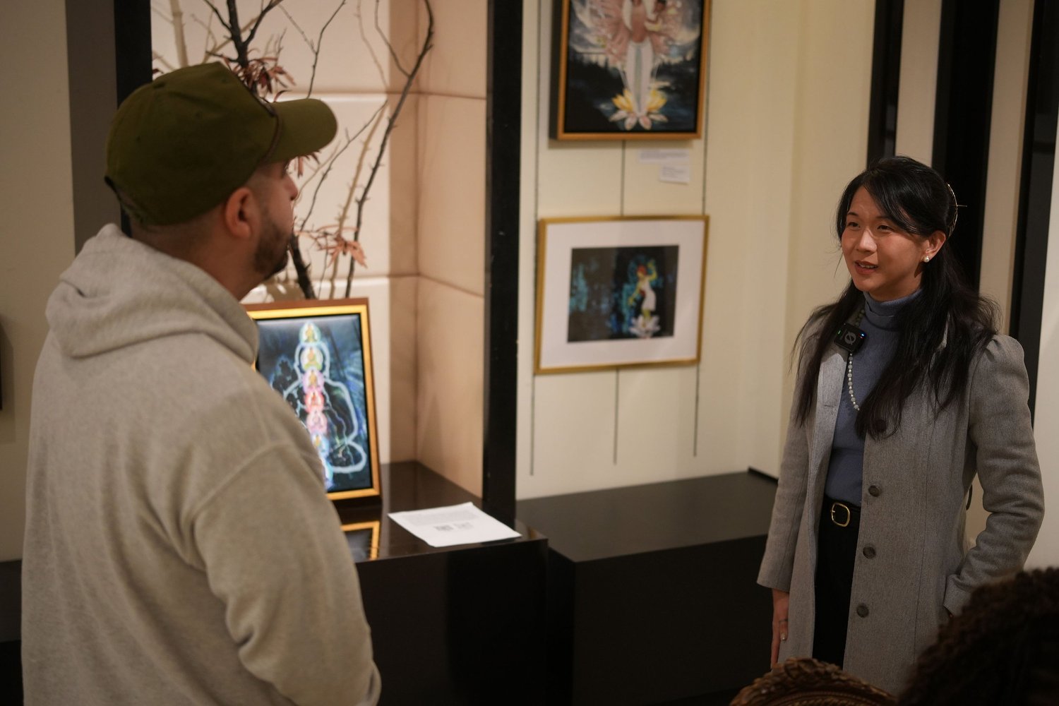 Two participants talk near a display of framed photographs.