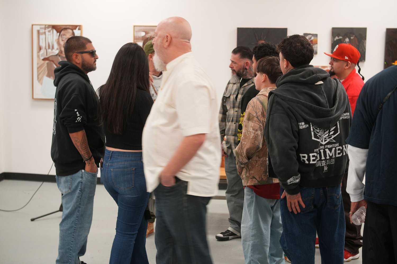 A group of visitors gathers beside framed portraits.