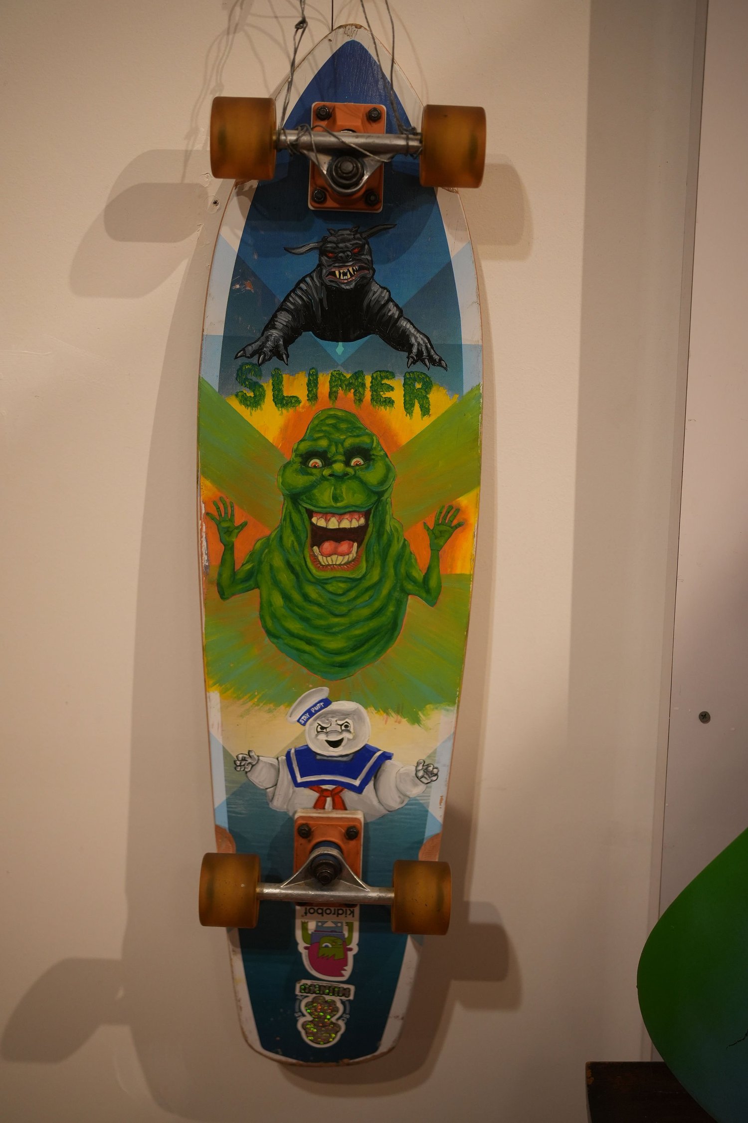A colorful longboard mounted vertically on the wall.