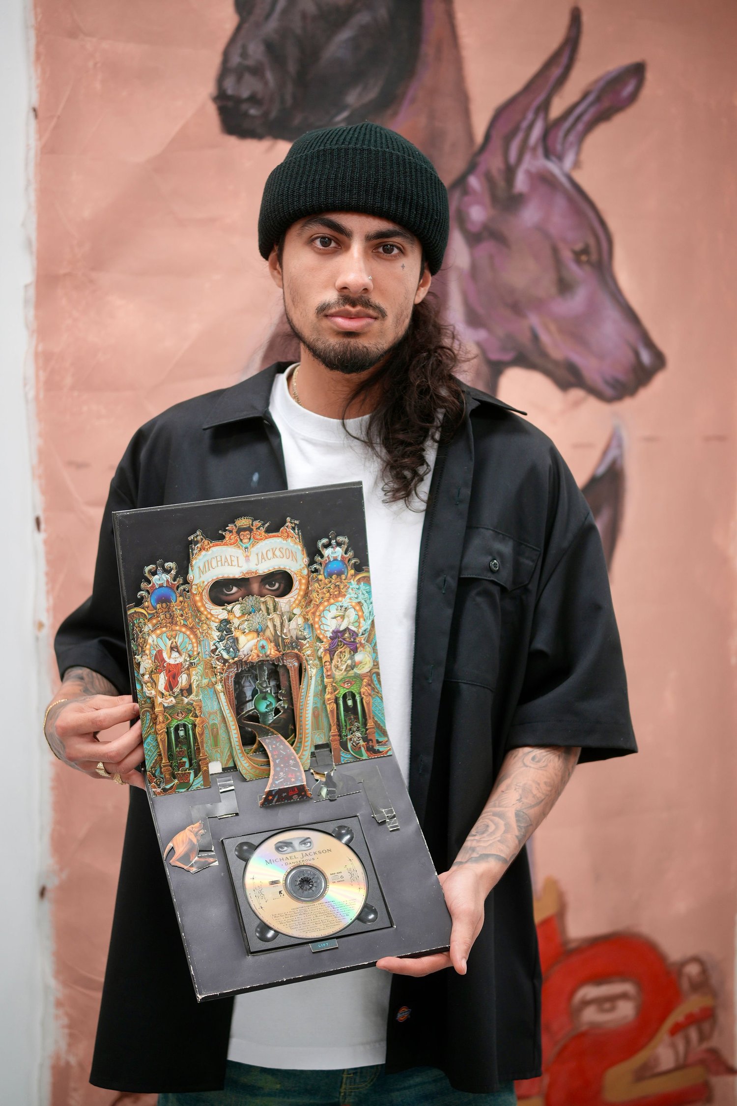 An artist displays a framed disc and artwork.