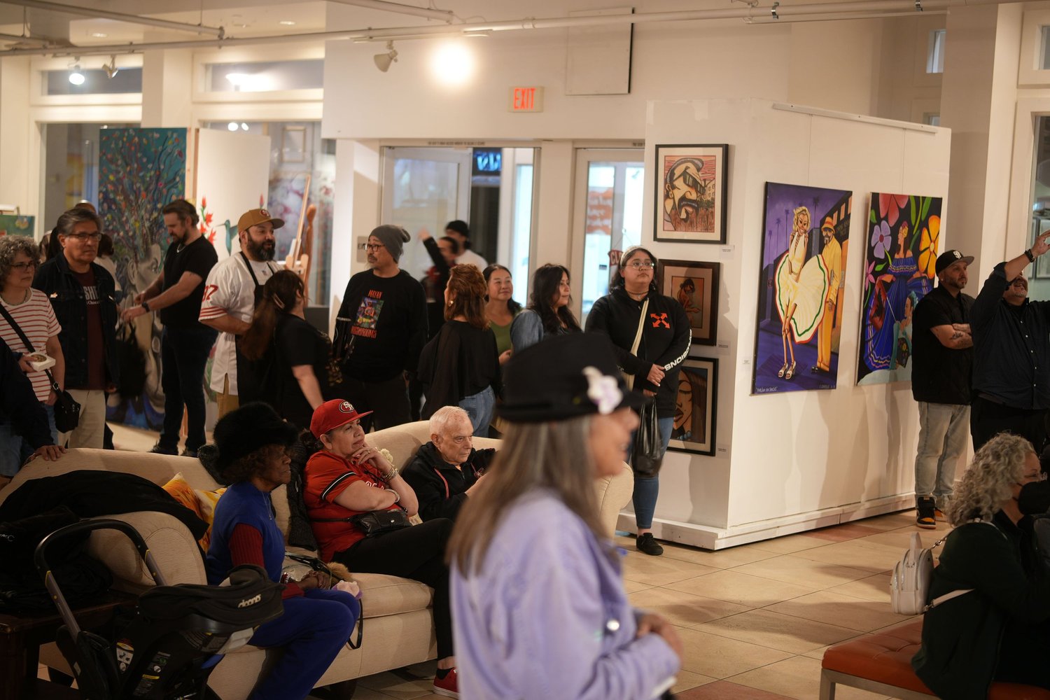 Guests gather and talk among the displayed artwork.