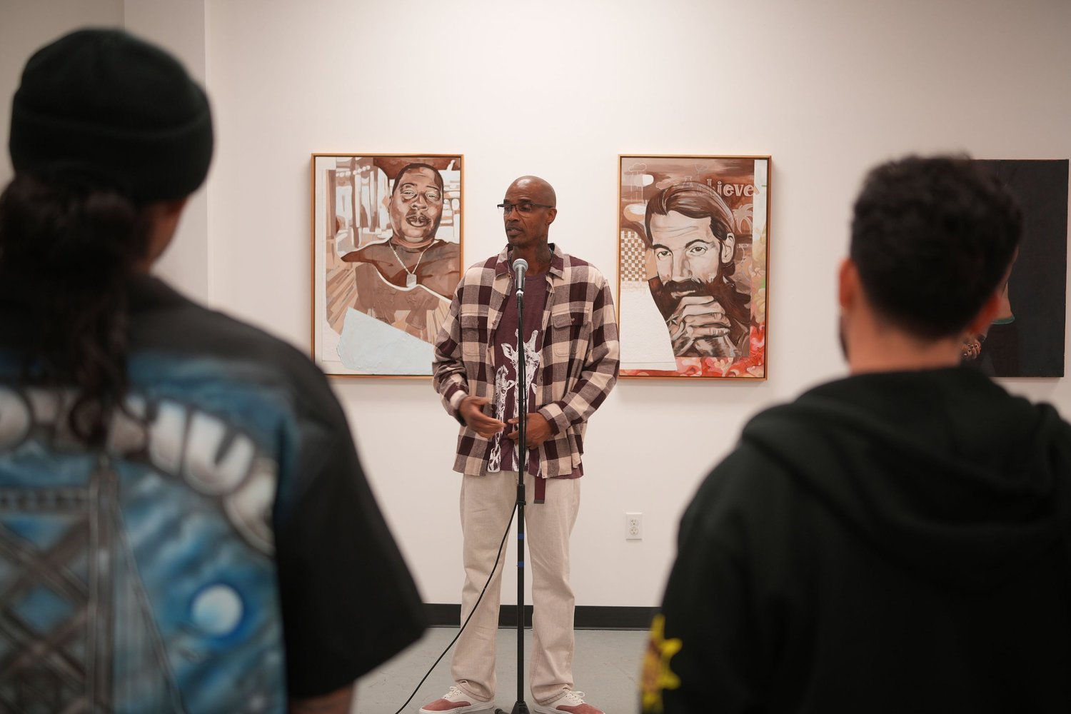 A speaker addresses gallery visitors with a microphone.