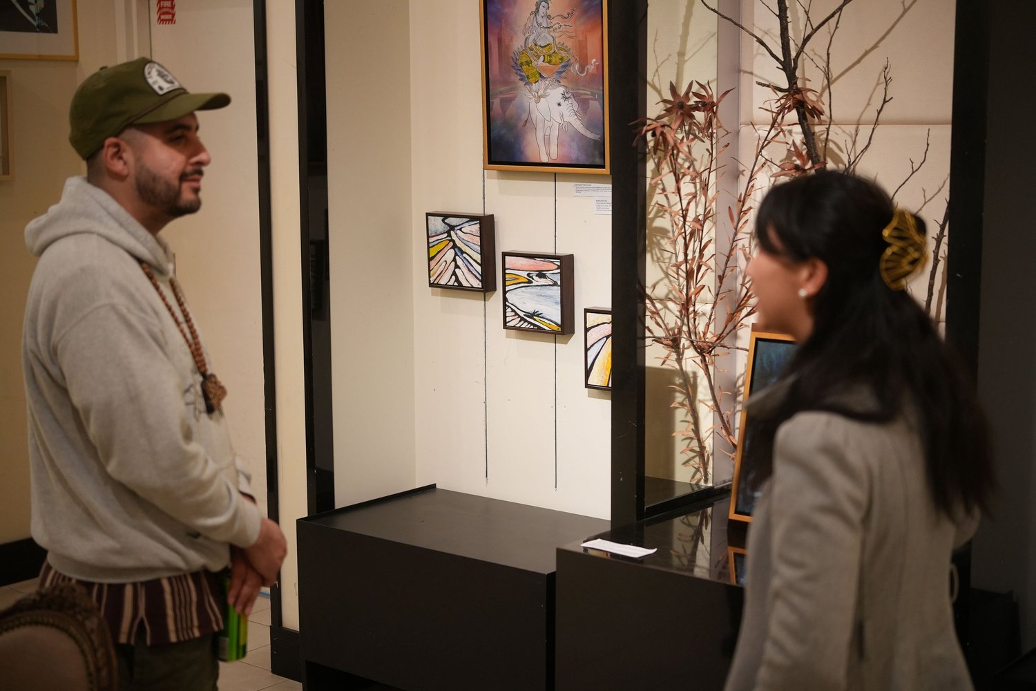 Two guests talk near a display of photographs.
