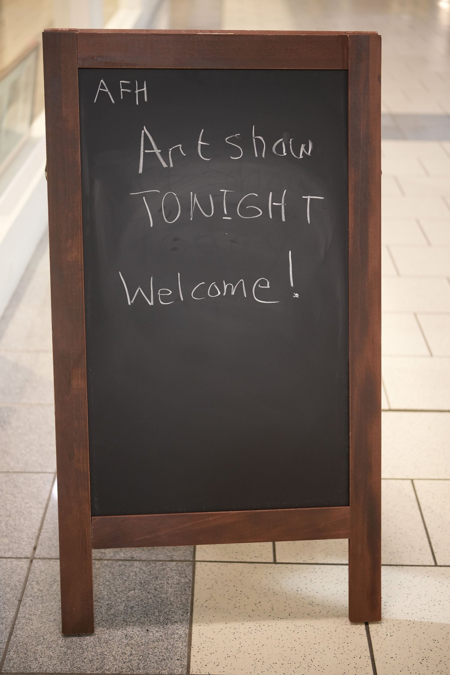 A chalkboard welcomes guests to an art show.