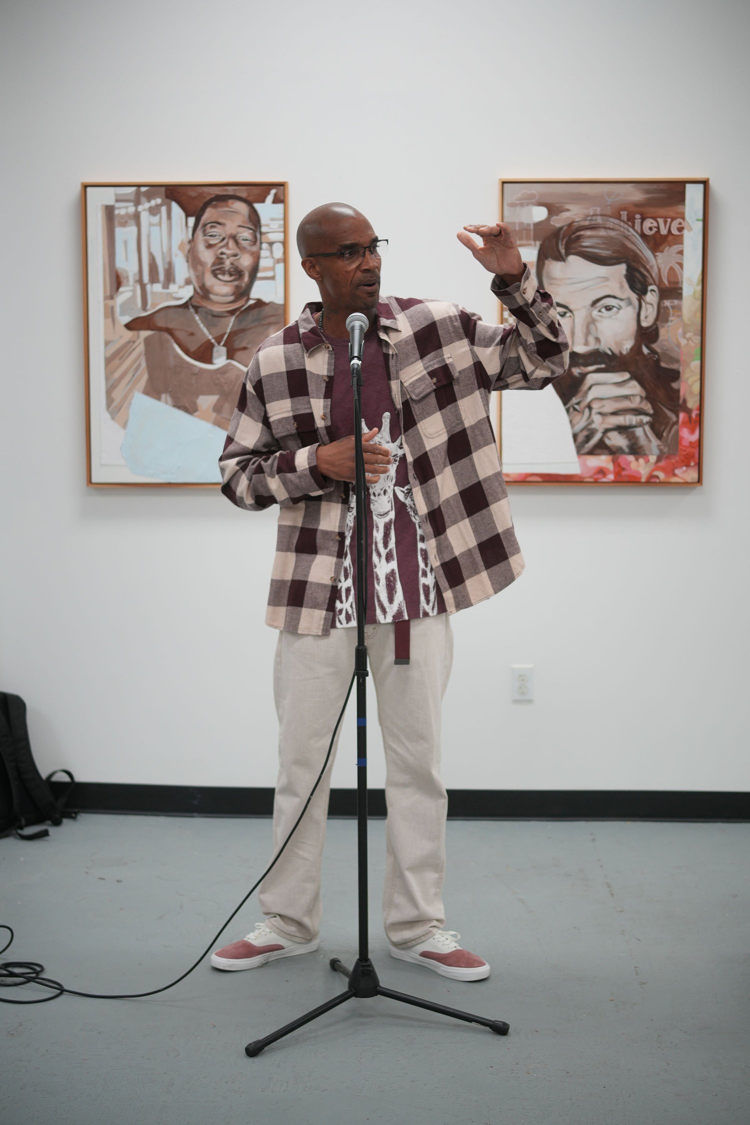 A speaker addresses gallery visitors with a microphone.