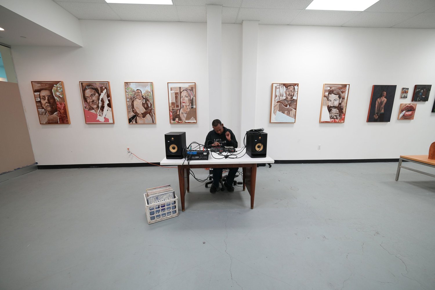 A DJ table stands beneath a row of painted portraits.