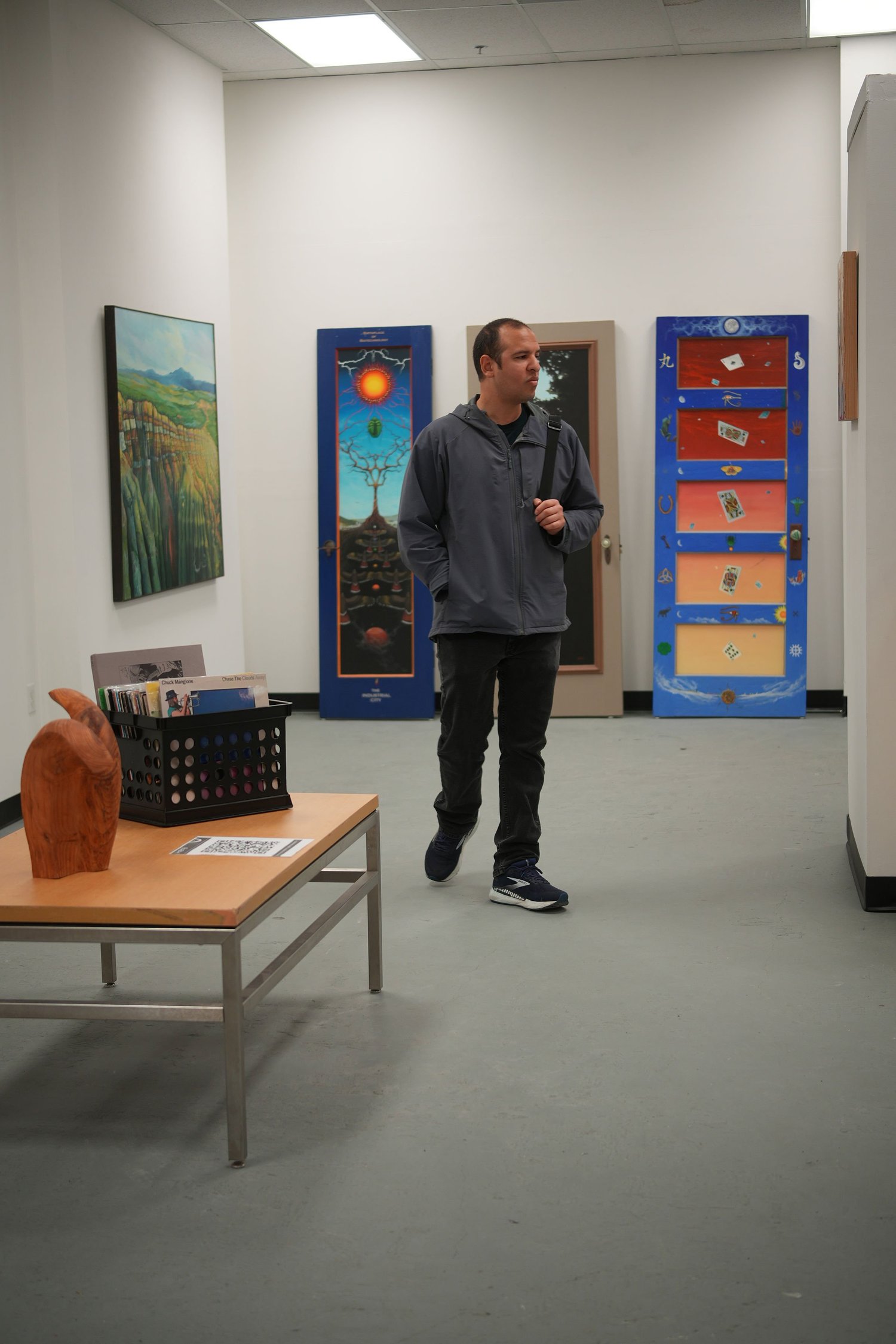 A visitor stands beside colorful paintings.