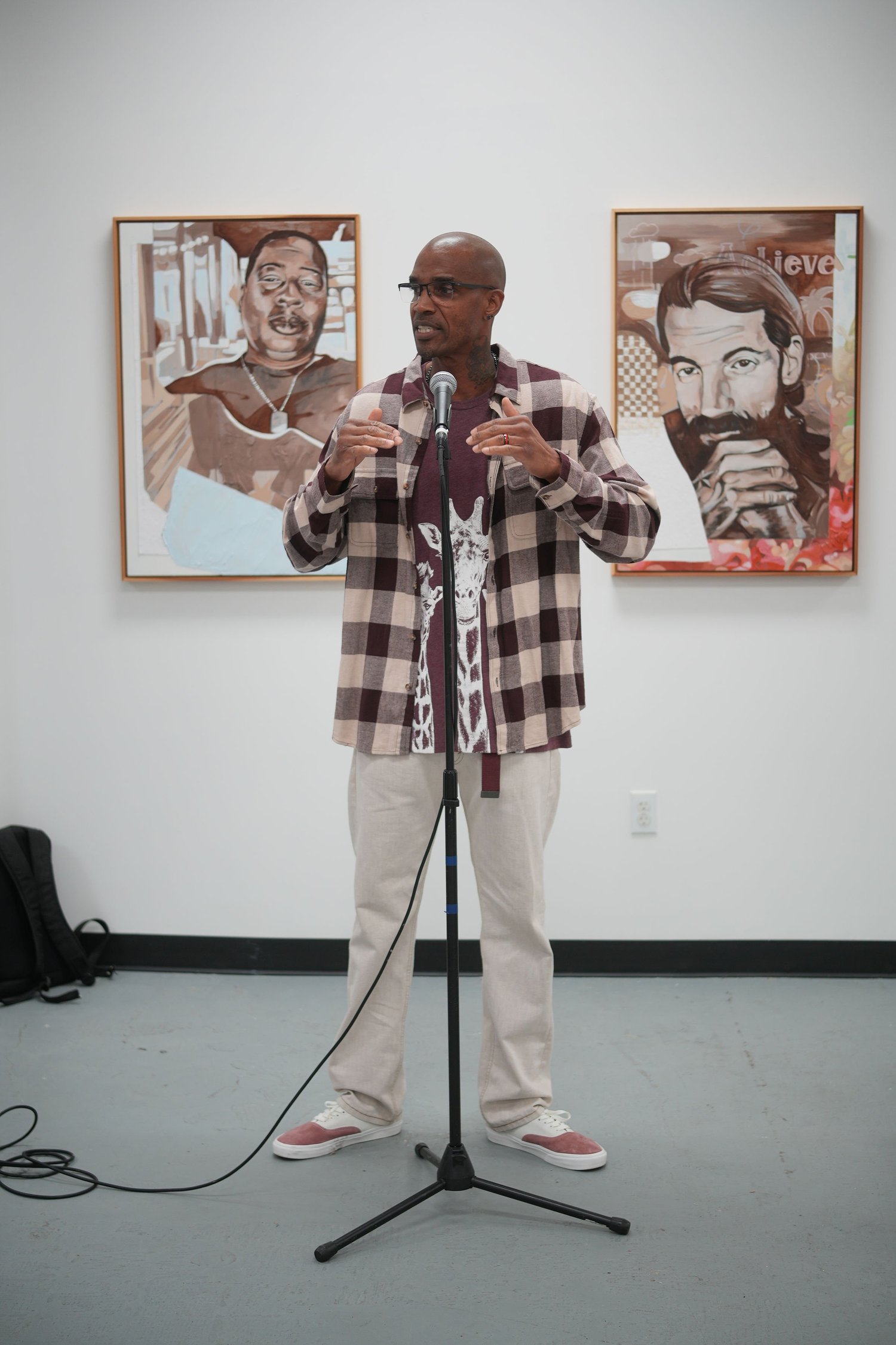 A speaker addresses gallery visitors with a microphone.