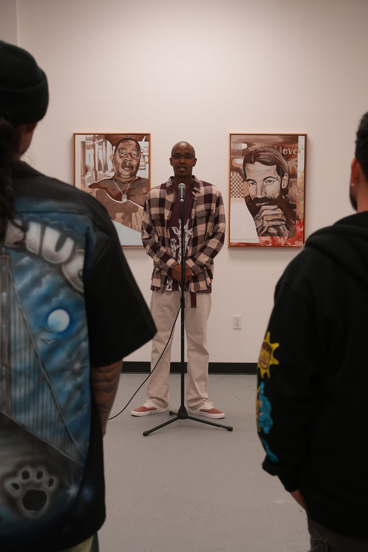 A speaker addresses gallery visitors with a microphone.