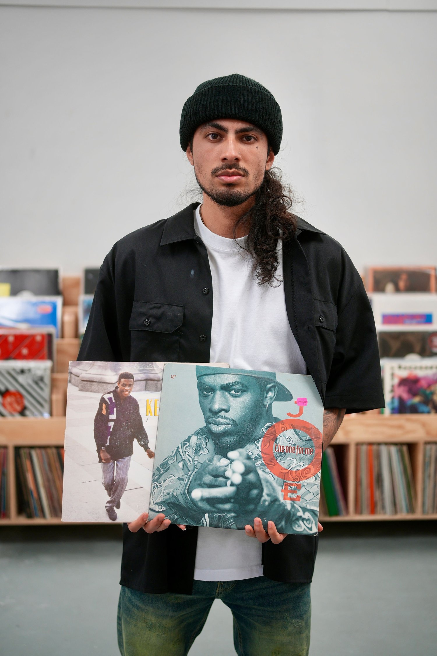 An artist holds vinyl record sleeves beside the collection.