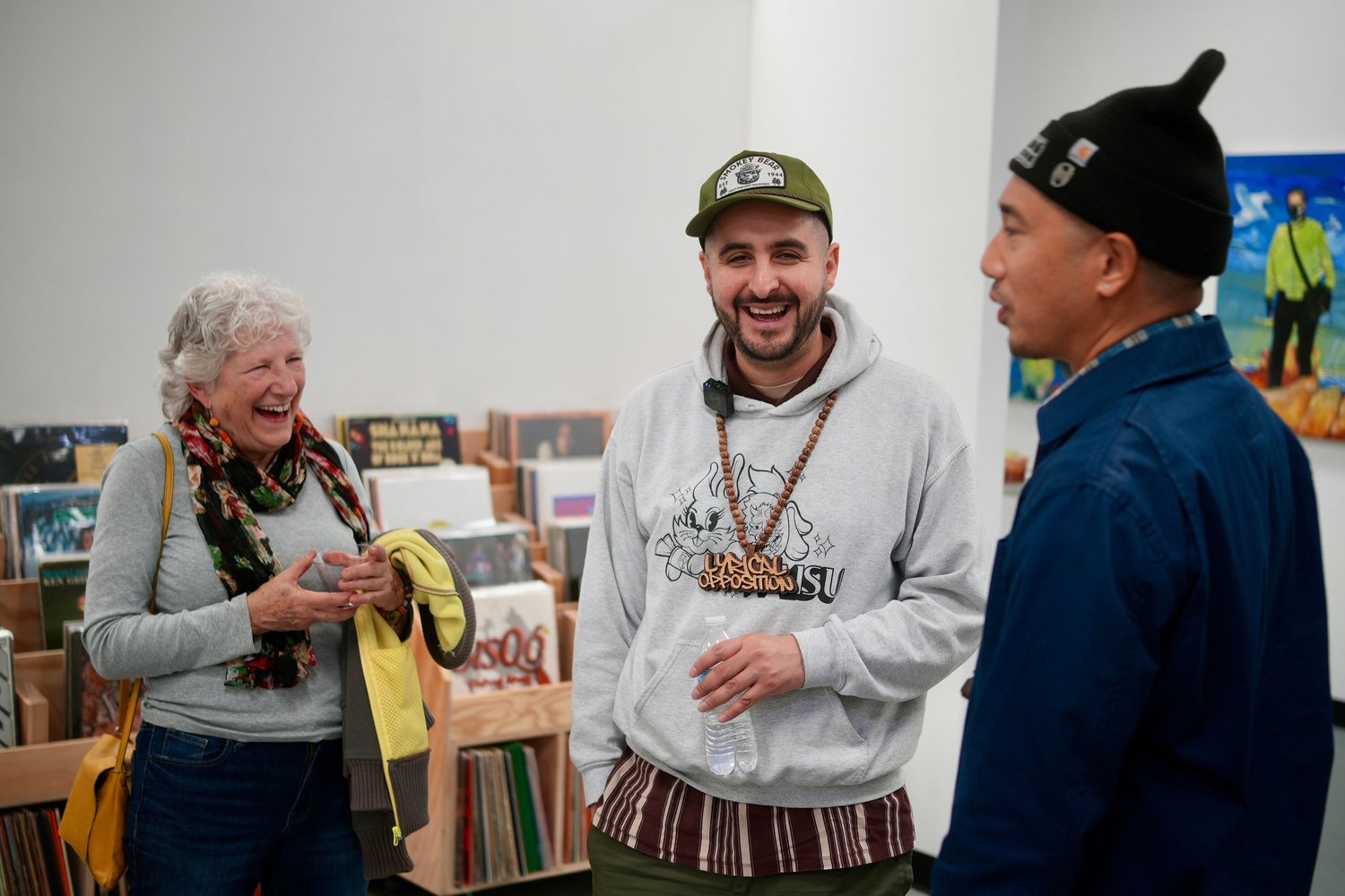 Three guests laugh beside shelves of records.