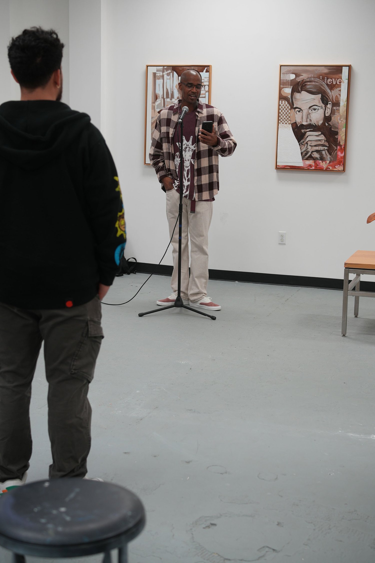 A speaker addresses gallery visitors with a microphone.