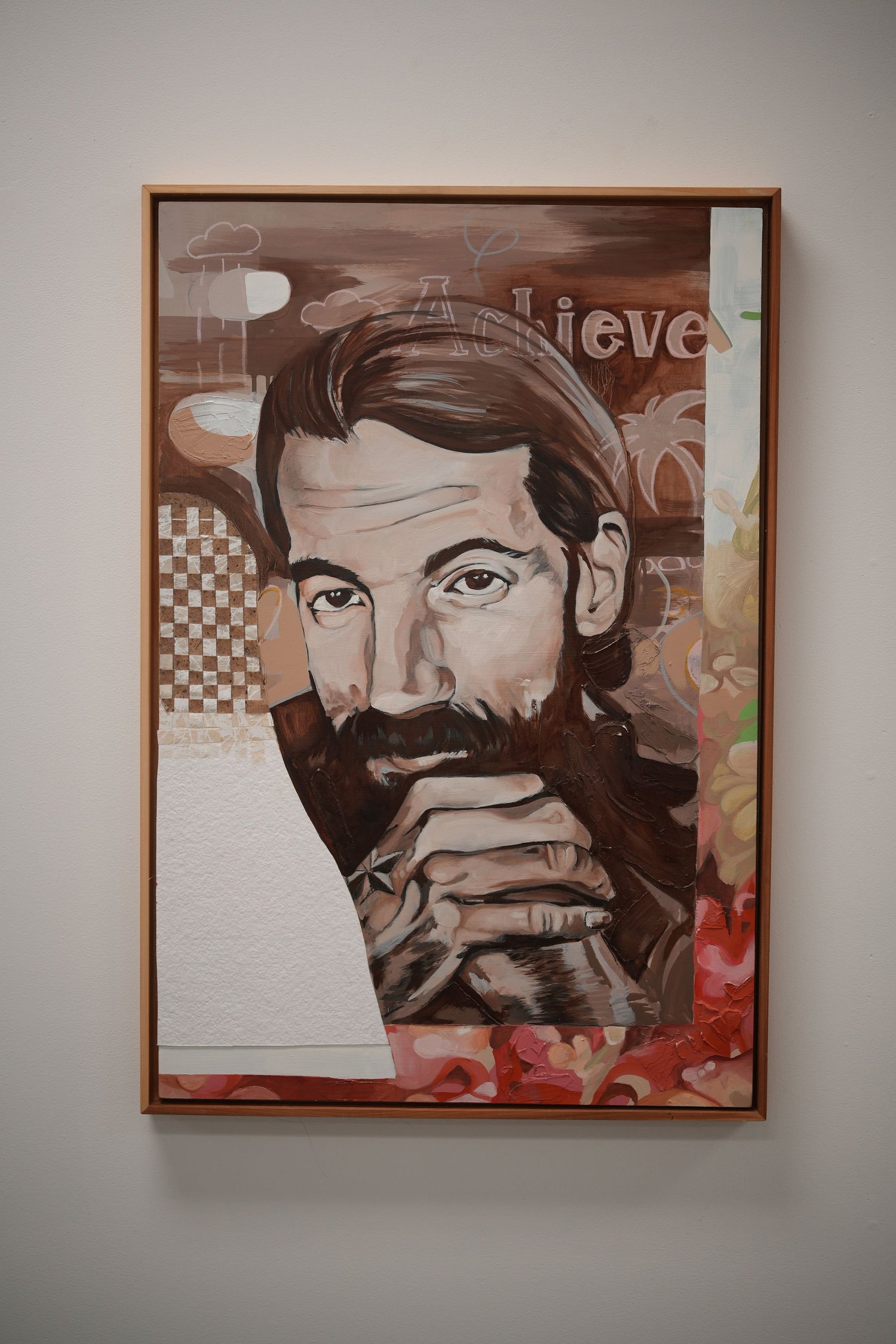 A framed portrait of a bearded person with clasped hands.