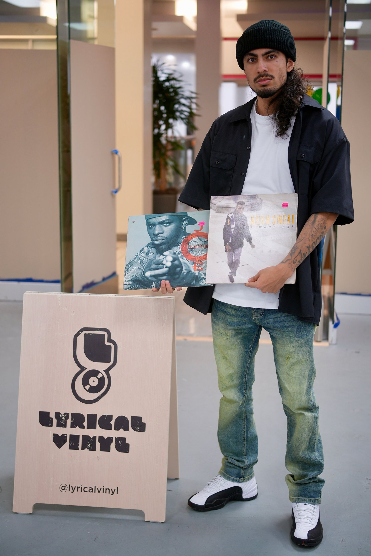 An artist holds vinyl record sleeves beside the collection.