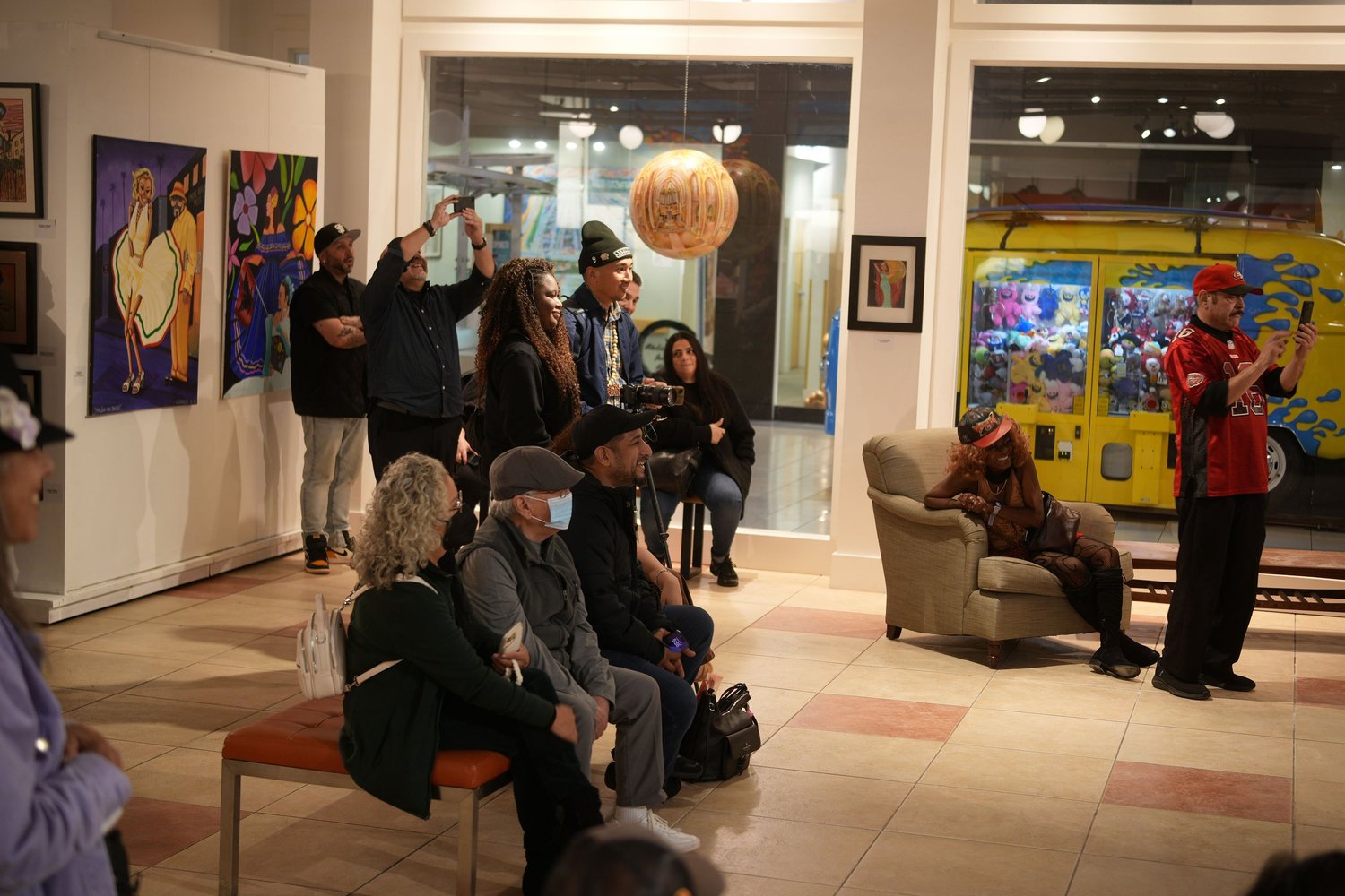 Guests gather and talk among the displayed artwork.