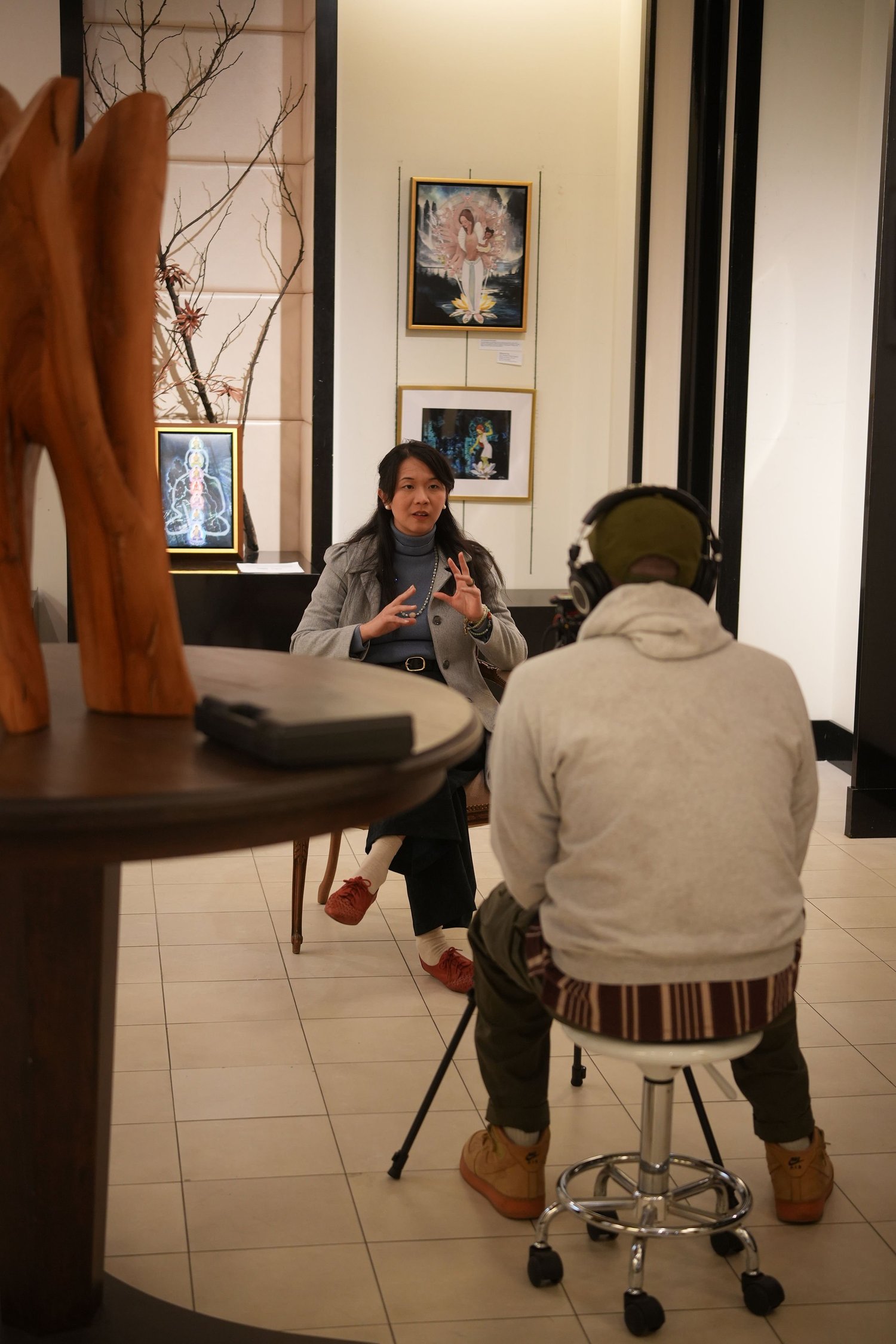 A seated participant speaks during a recorded gallery interview.