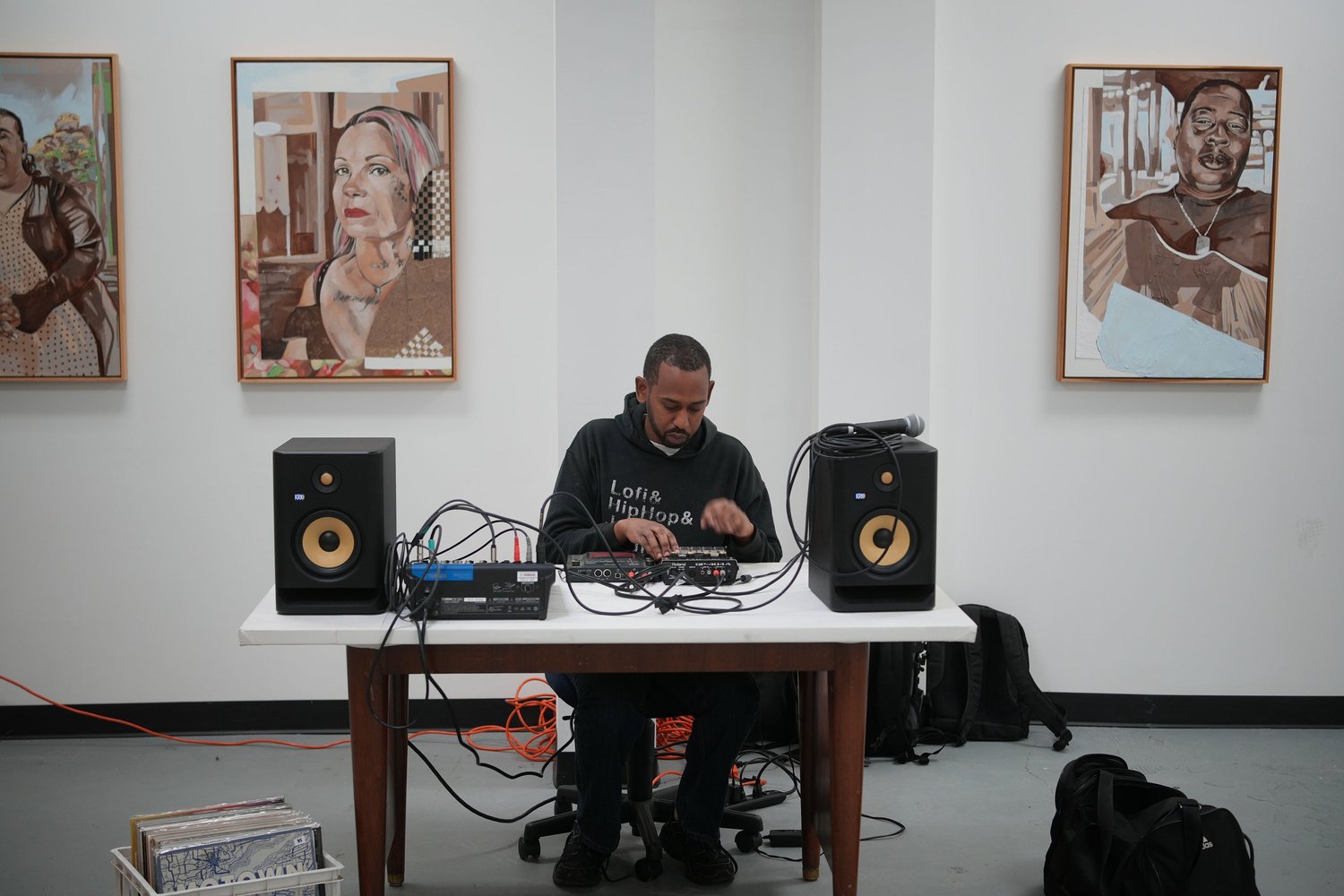 A DJ operates turntables beneath framed portraits.