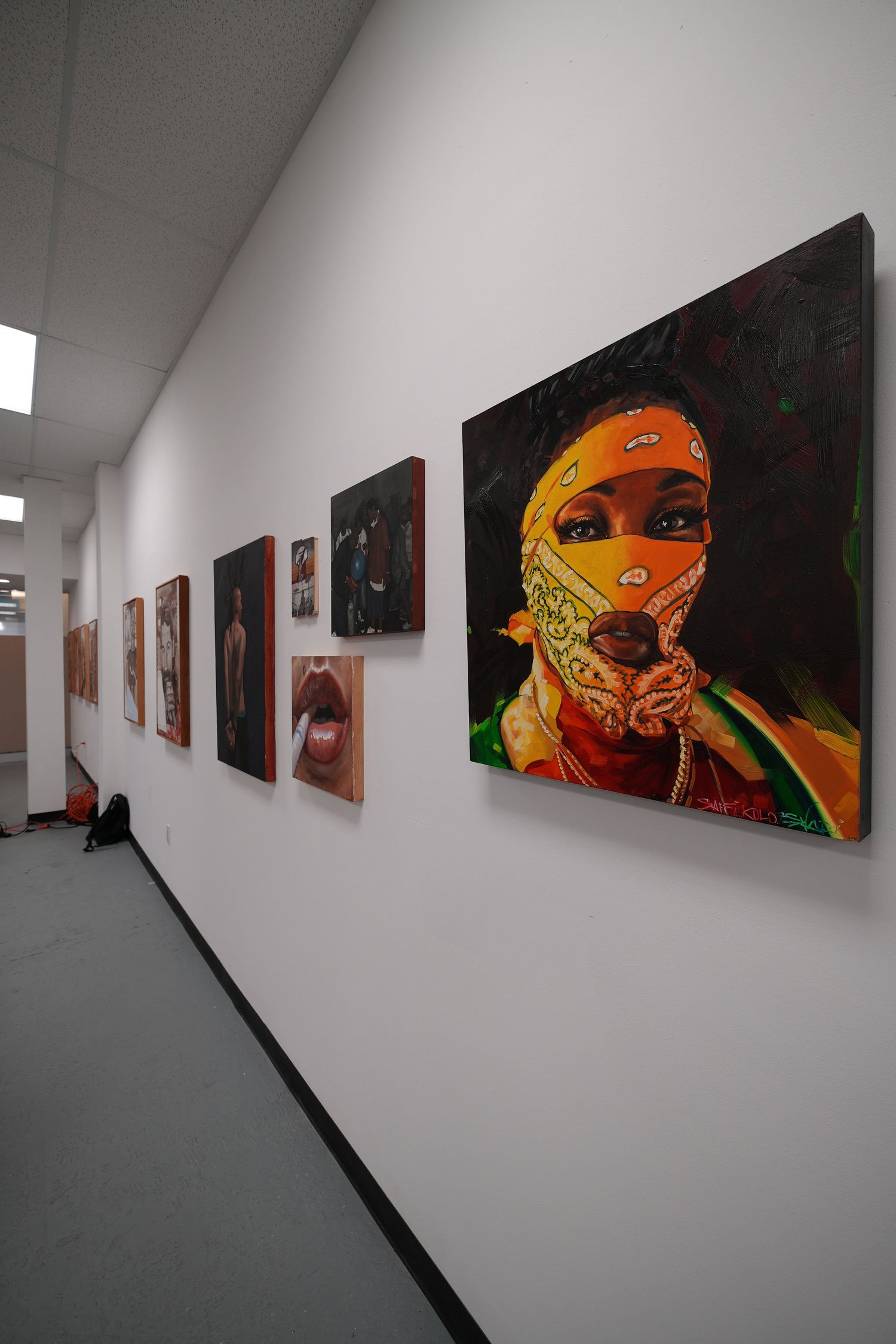 Paintings displayed along a white gallery wall.