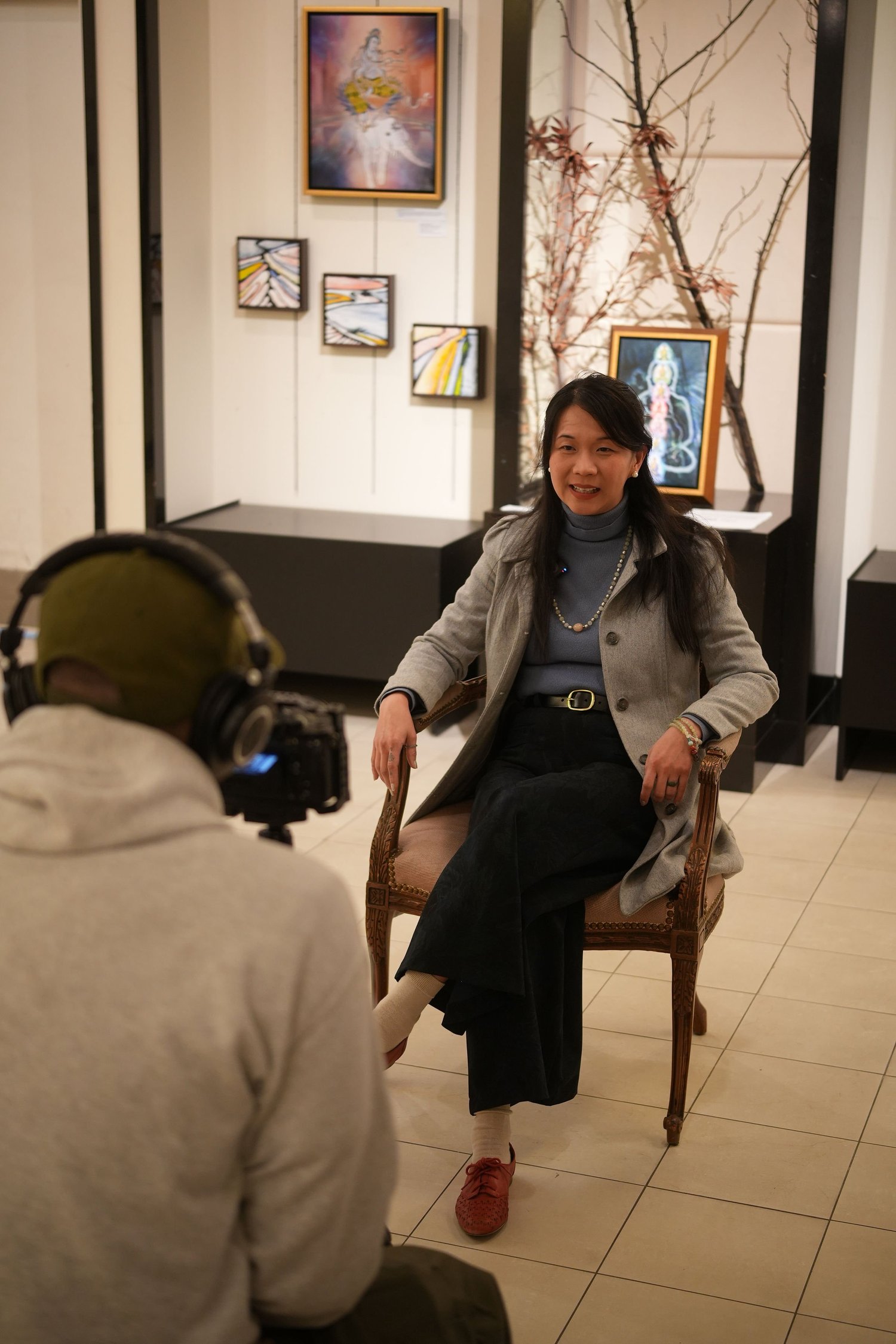 A seated participant speaks during a recorded gallery interview.