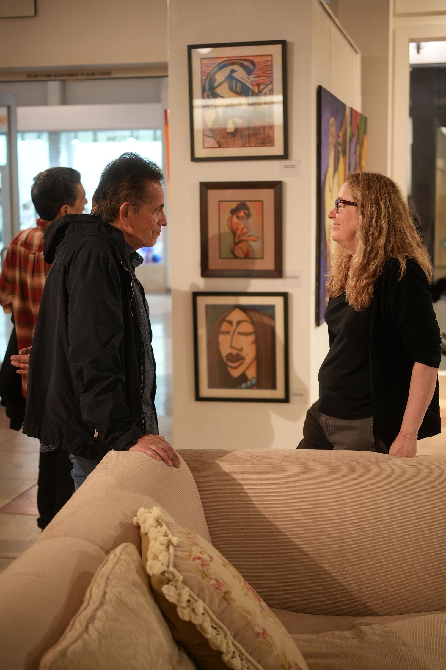 Visitors converse among the gallery artwork.