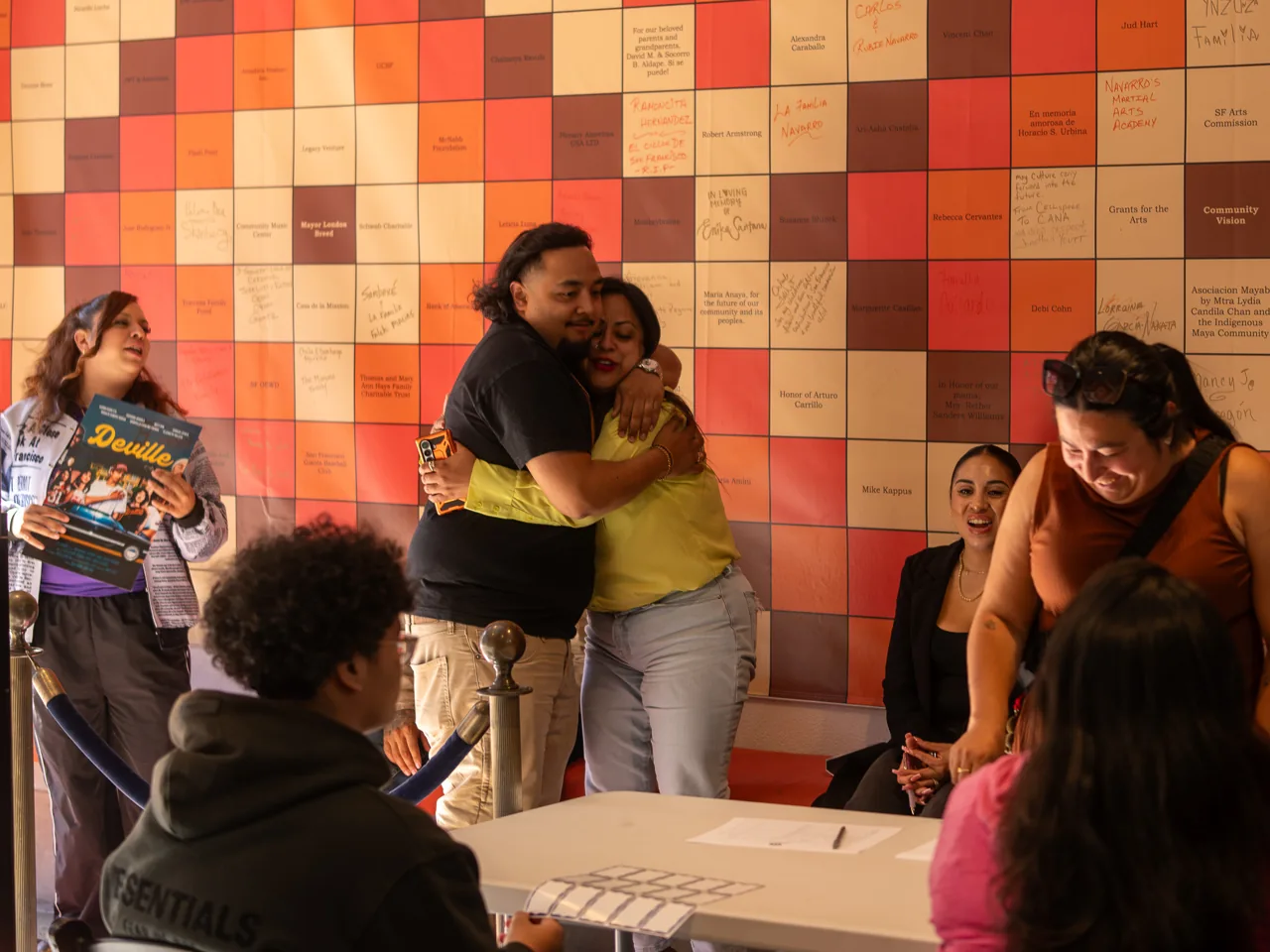 Two guests embrace beside the welcome table.